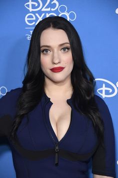 a woman with long black hair wearing a blue dress and red lipstick is posing for the camera