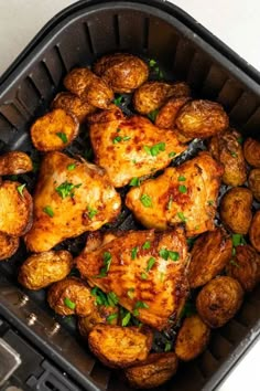 chicken and potatoes in an air fryer with parsley garnish on top