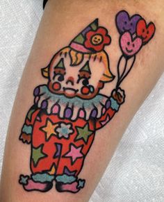 a colorful tattoo with an image of a clown holding hearts and stars on his leg