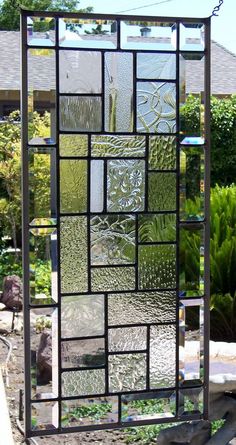 a stained glass window sitting on top of a metal frame in front of a house