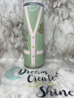 a green and pink can with the words dream create shine on it next to a marble background