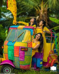 two women sitting on top of a colorful car