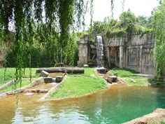 an artificial pond in the middle of a park with water flowing from it's sides