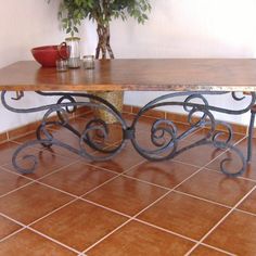 a wooden table sitting on top of a tiled floor next to a potted plant