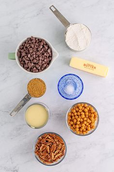 the ingredients to make chocolate pecan bars are shown in bowls on a marble countertop