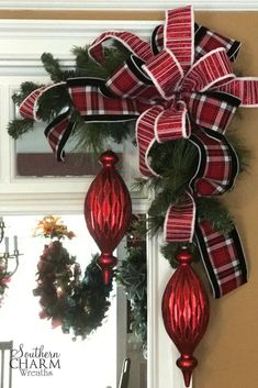 a red and black christmas ornament hanging on the front door with a bow