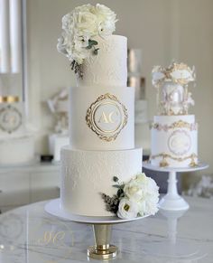 a three tiered wedding cake with white flowers on the top and gold trimmings