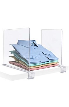 a stack of folded shirts in a clear acrylic holder on a white background