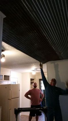 two men working on a ceiling in a kitchen