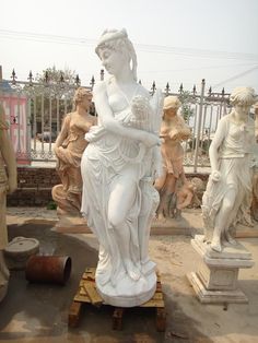 a statue is sitting on a cart in front of other statues, including women and men