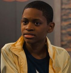 a young boy in a yellow jacket looking at the camera with an intense look on his face