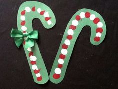 two candy canes are decorated with red and white polka dots on green paper, one has a bow