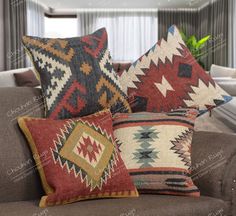 three colorful pillows sitting on top of a brown couch