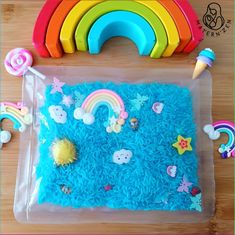 a cake with blue frosting and rainbows on it, surrounded by plastic toys