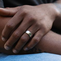 a close up of a person with a ring on their hand and tattoos on his arm