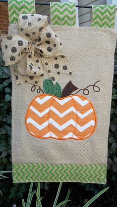 an orange and white pumpkin on a burlock with polka dot ribbon hanging from a clothes line