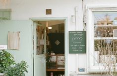 an open door to a store with plants in the foreground and signs on the wall