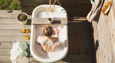 a woman sitting in a bathtub on top of a wooden deck