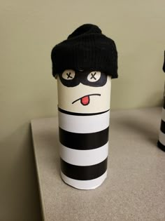 a black and white striped cup with a hat on it's head sitting on a counter