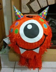 an orange monster pillow sitting on top of a tiled floor next to a fire place