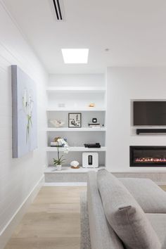 a modern living room with white walls and wood flooring, built - in shelving