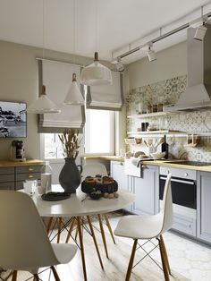 a white table and chairs in a small room with an open kitchen area behind it