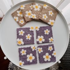 four crocheted coasters on a white plate with yellow and purple daisies