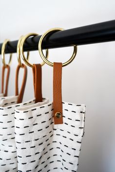 three pairs of scissors hanging from hooks on a rail with black and white patterned fabric