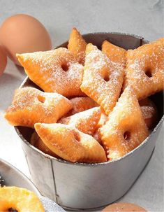 several pastries are in a metal container next to eggs