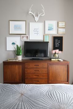 a bed with a television on top of it next to pictures and other things hanging on the wall