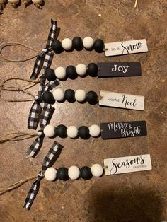 three black and white beaded necklaces with name tags hanging from them on a table