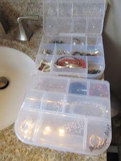 the bathroom sink is filled with jewelry and bracelets in plastic storage boxes next to a roll of toilet paper