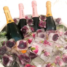 several bottles of champagne and ice cubes with flowers on them in an ice bucket