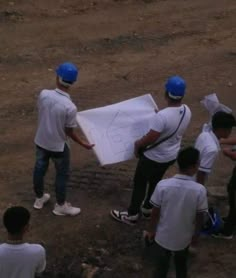 a group of young men standing next to each other on top of a dirt field