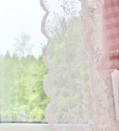 a cat sitting on the window sill looking out at the trees and grass outside