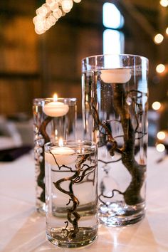 candles are placed in glass vases on a table