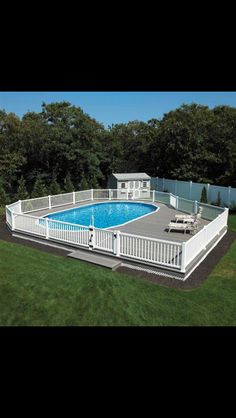 an above ground swimming pool surrounded by grass and trees with white fence around it, in the middle of a yard