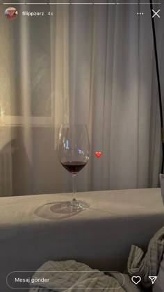 a glass of wine sitting on top of a bed