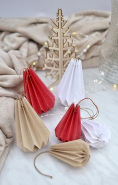 four folded paper umbrellas sitting on top of a white table next to a christmas tree