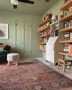 a living room filled with furniture and bookshelves next to a green chair in front of a book shelf