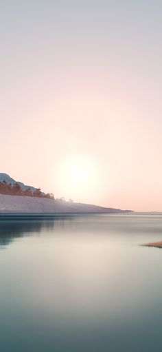 the sun is setting over a calm lake