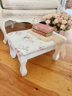 a white bench sitting on top of a hard wood floor next to a flower vase