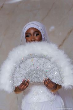 a woman in a wedding dress holding a white fan with sequins on it