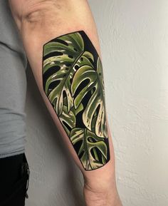 a man's arm with a green and black monster plant tattoo on the left upper arm