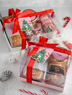 three boxes filled with cookies and candy canes on top of a white tablecloth