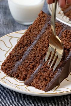 someone is holding a fork over a piece of chocolate cake