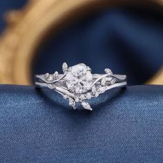 a close up view of a diamond ring with leaves on it's sidestone