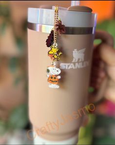 a person holding a coffee cup with charms on it