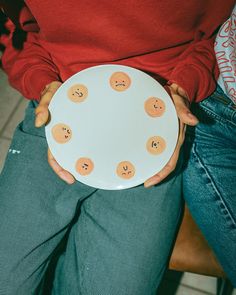 a person holding a plate with smiley faces on it