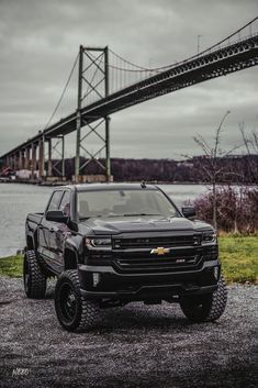 a black truck parked in front of a bridge